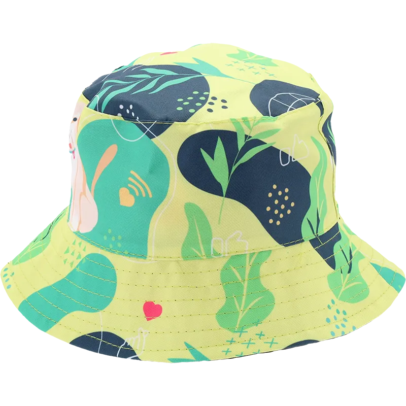 A yellow bucket hat with a colorful abstract pattern featuring green leaves, navy shapes, and a pink bunny illustration, shown on a plain white background.