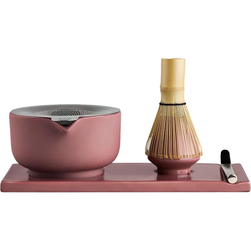 Fellow matcha tea set on a rectangular tray, featuring a dusty pink ceramic bowl with a metal lid, a bamboo whisk, and a small metal scoop on a solid white background.