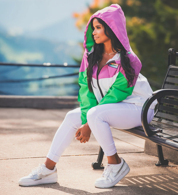 Woman sitting on a bench wearing a colorful jacket with a hood