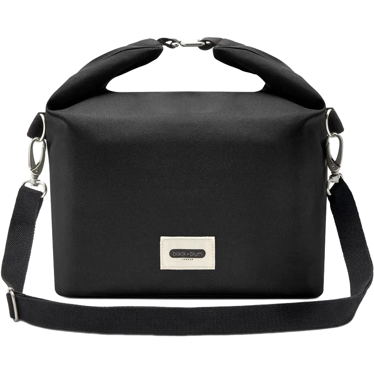 A black roll-top crossbody bag with a top handle, adjustable shoulder strap, and a silver-tone metal brand plaque on the front, shown against a plain white background