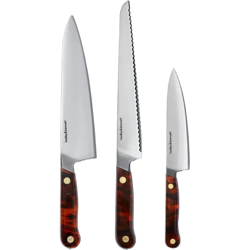 Three Hedley & Bennett kitchen knives with silver stainless steel blades and tortoiseshell-patterned brown handles with brass rivets, displayed vertically against a white background.