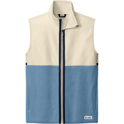 A color-blocked zip-up vest with a cream upper section and a slate blue lower section, featuring a dark navy zipper and a small white logo patch on the bottom right.