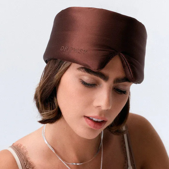 Woman wearing a brown Drowsy satin head wrap on a light gray background