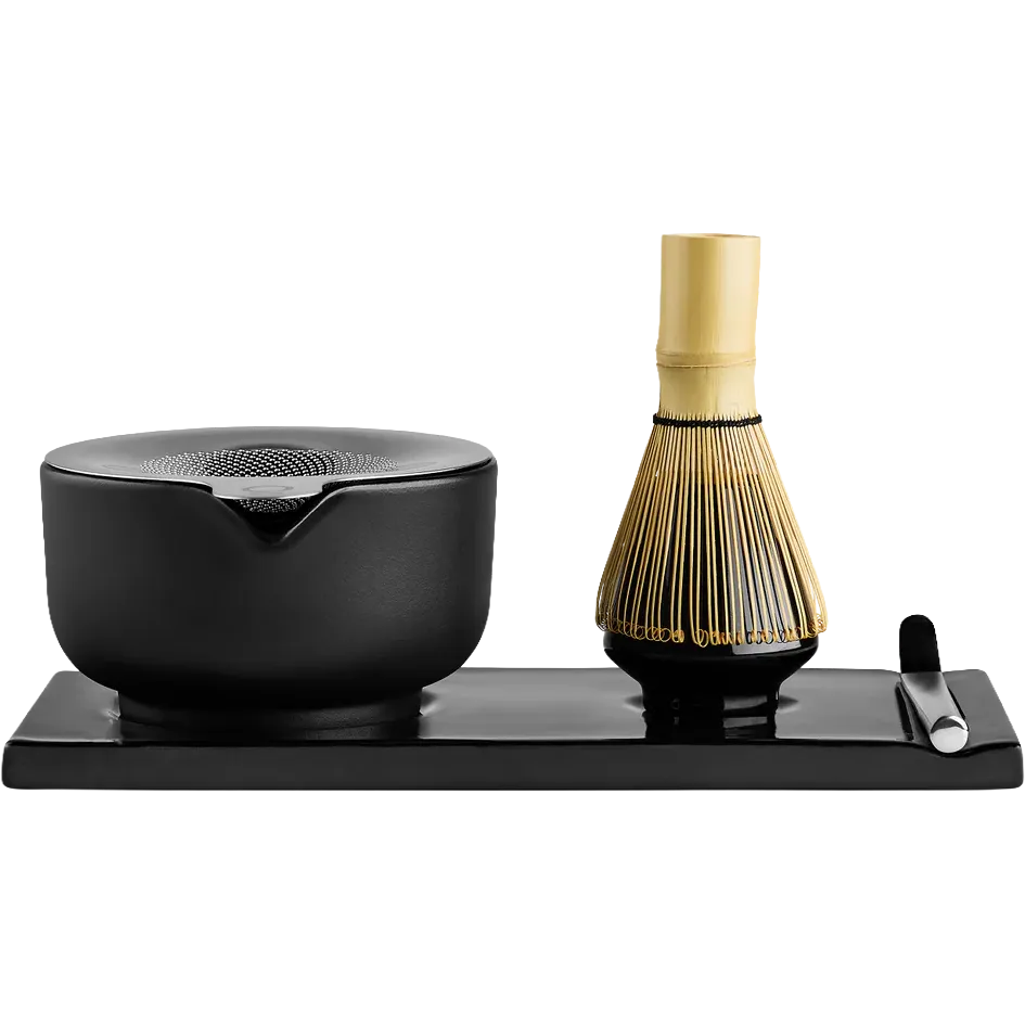 Fellow matcha tea set on a rectangular black tray, featuring a black ceramic bowl with a pouring spout, a bamboo whisk with a gold-toned handle, and a small black spoon on a white background.