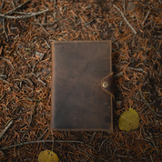 Brown leather wallet on a textured brown surface with leaves
