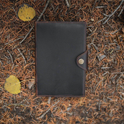Black leather notebook with brown leather binding on a textured surface