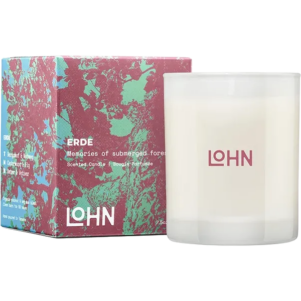 A frosted glass scented candle next to its colorful box. The candle is white with the brand name 'LOHN' printed in pink on the front.