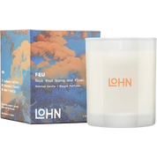 A scented candle in a frosted white glass jar next to its illustrated packaging box. The box features a blue and orange cloud design with the brand name LOHN and the scent name FEU printed on it.
