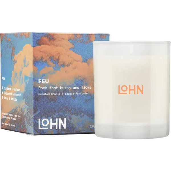 A scented candle in a frosted white glass jar next to its illustrated packaging box. The box features a blue and orange cloud design with the brand name LOHN and the scent name FEU printed on it.