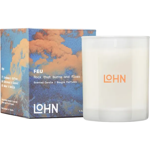 A scented candle in a frosted white glass jar next to its illustrated packaging box. The box features a blue and orange cloud design with the brand name LOHN and the scent name FEU printed on it.