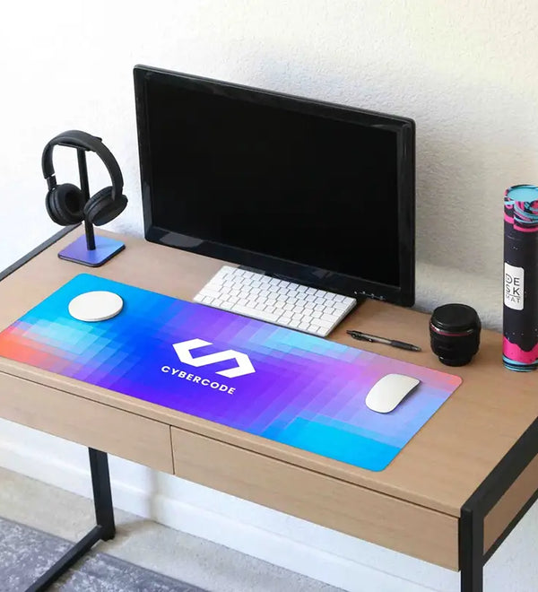 Wooden desk with computer setup including a monitor, keyboard, mouse, and large mouse pad with 'Cybercode' branding.