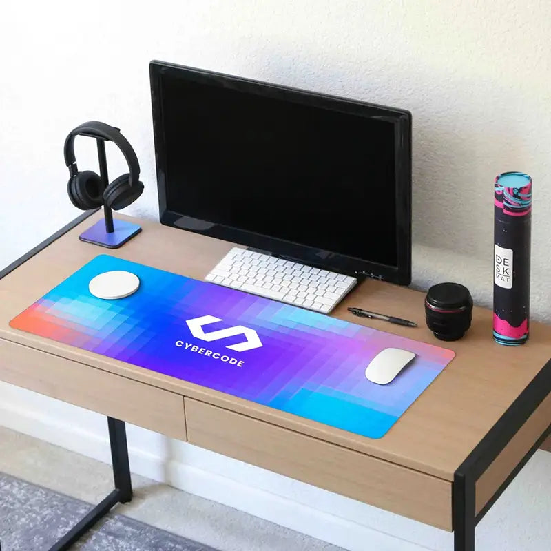 Wooden desk with computer setup including a monitor, keyboard, mouse, and large mouse pad with 'Cybercode' branding.