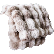 A plush faux fur throw blanket with a wavy, ribbed texture in shades of beige, cream, and light brown, isolated on a white background.