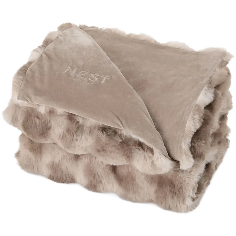 A folded plush throw blanket with a soft taupe fleece top and a lighter beige faux fur border, featuring the brand name 'NEST' embroidered on the fleece side.