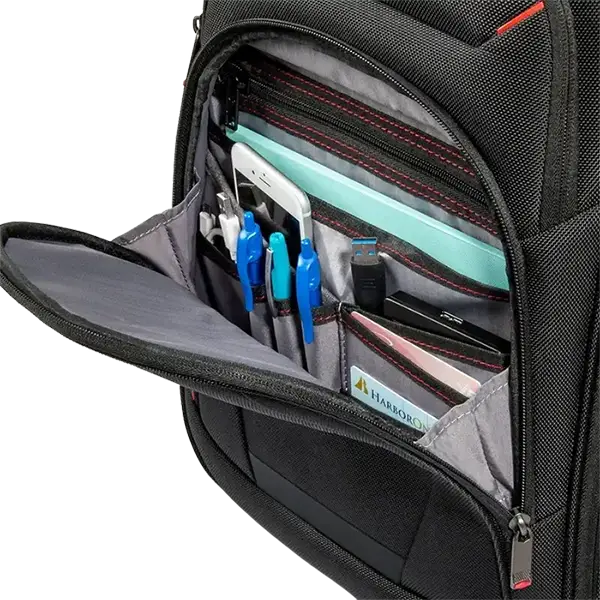 Close-up of an open black backpack showing organized interior compartments with red stitching, pen slots, a light blue folder, pens, a smartphone, and other accessories. A small card on the inside pocket shows the brand HARKKON.